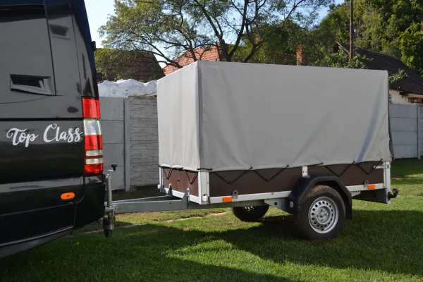 Prívesný vozík s plachtou zapojený za čiernym minibusom
